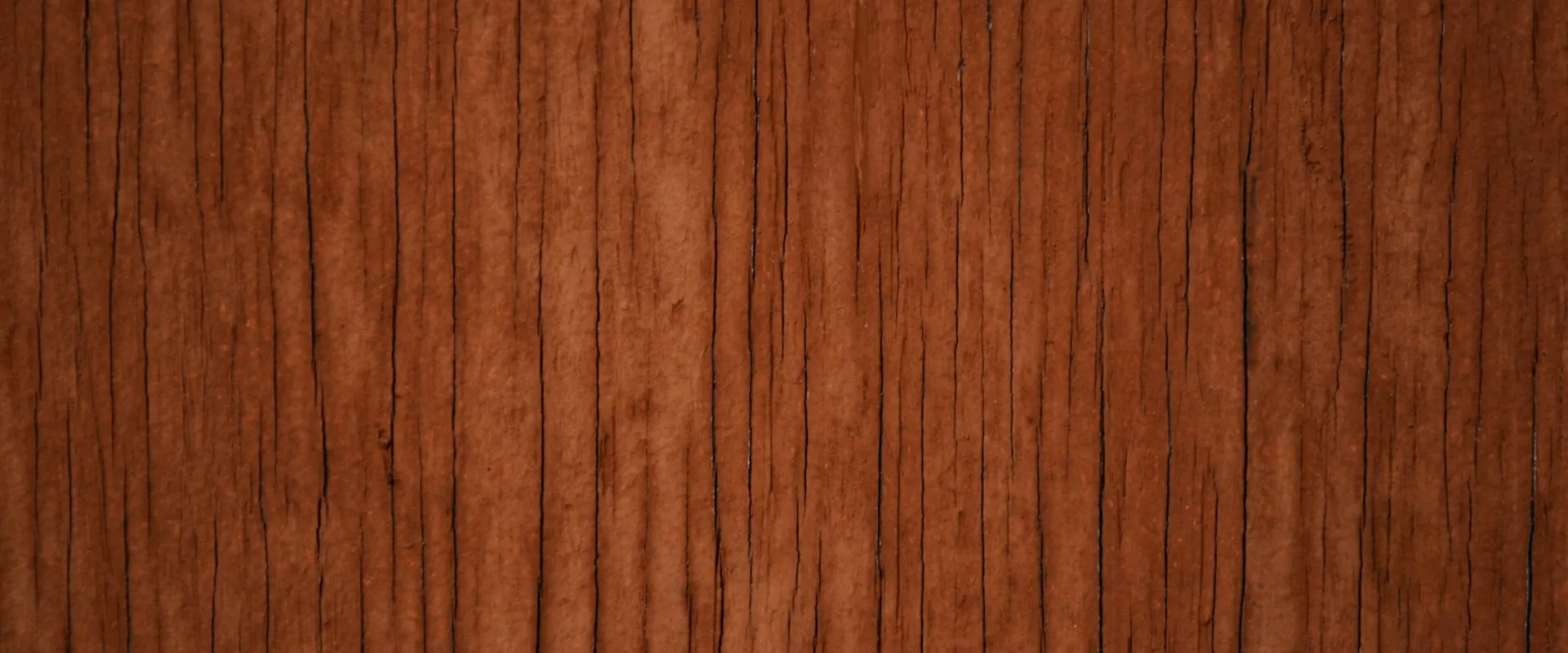 A close-up of dark brown wood grain with vertical cracks